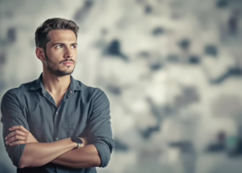 Person with crossed arms looking thoughtful in soft light. Explore fixed mindset def, its traits, and effects on growth. Learn to shift towards a growth mindset.