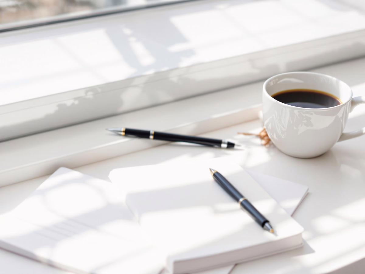 Minimalist workspace with journal and coffee cup.